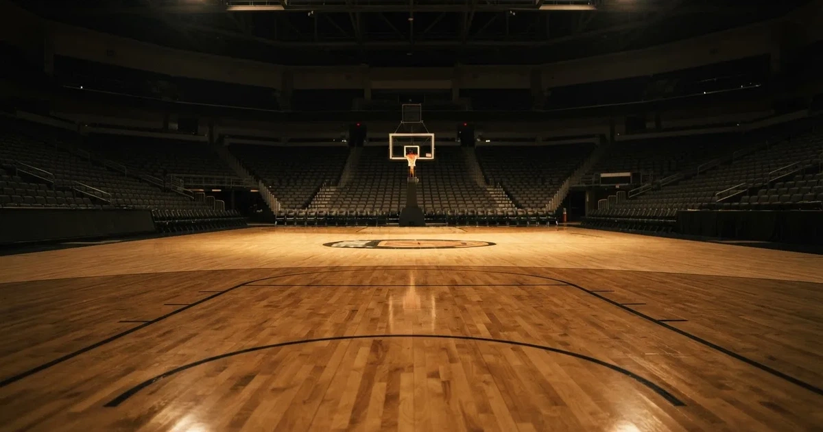 Eine leere Basketballhalle mit glänzendem Parkett und einem Korb im Hintergrund, Licht von Deckenstrahlern spiegelt sich im Boden.
