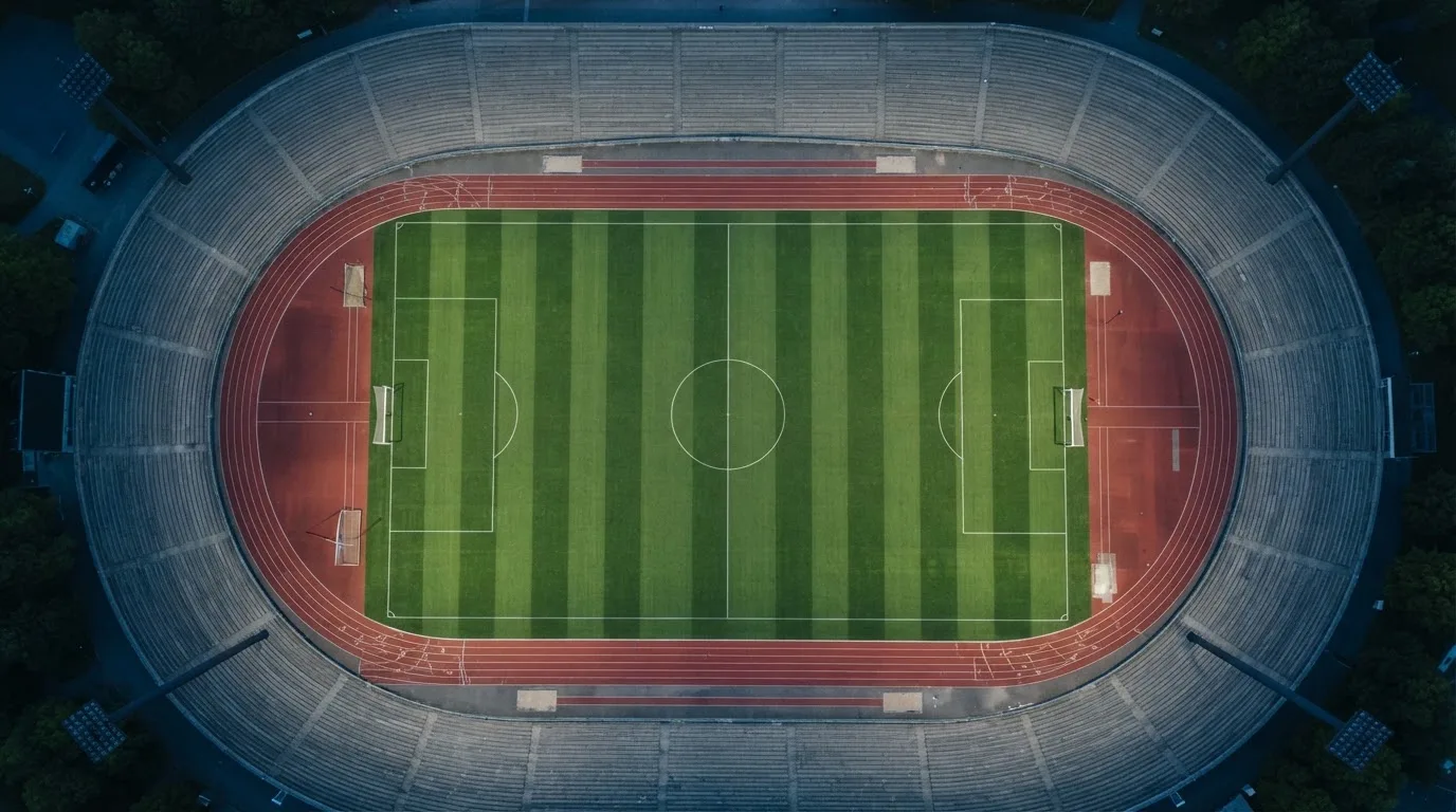 Ein Fußballplatz am Abend aus der Vogelperspektive, Flutlichtmasten ausgeschaltet, die Rasenlinien deutlich sichtbar.