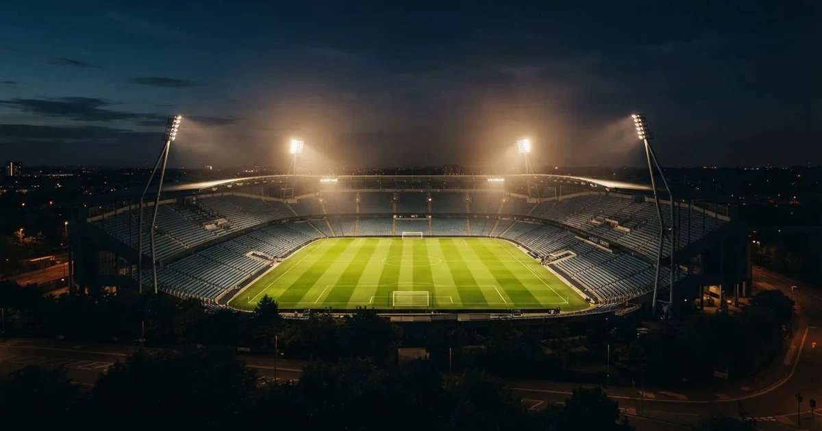 Ein Stadion bei Nacht unter Flutlicht aus der Ferne gesehen, der Rasen ist hell erleuchtet, keine erkennbaren Personen.