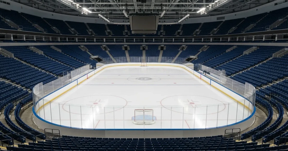 Eine Eishockeyhalle von der Tribüne aus gesehen, spiegelglatte Eisfläche, Banden ohne Schriftzüge, helles Flutlicht.